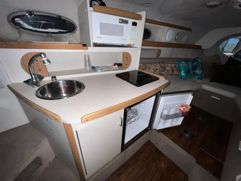 Slide: The Image of 1997 Four Winns 258 Vista boat interior with kitchenette, microwave, sink, and mini-fridge. - 26