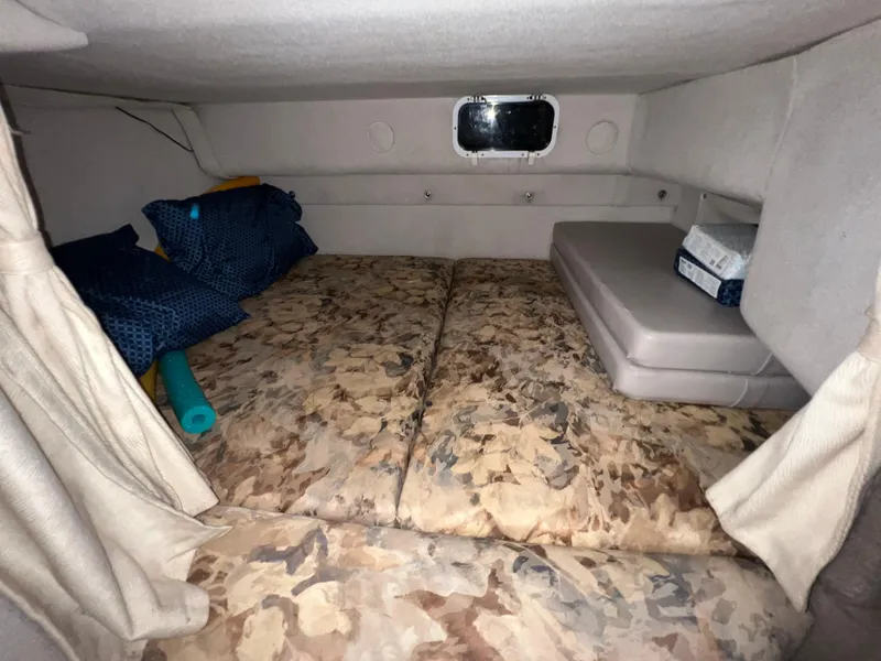 Slide: The Image of 1997 Four Winns 258 Vista cabin interior with camouflage bedding and small window. - 29