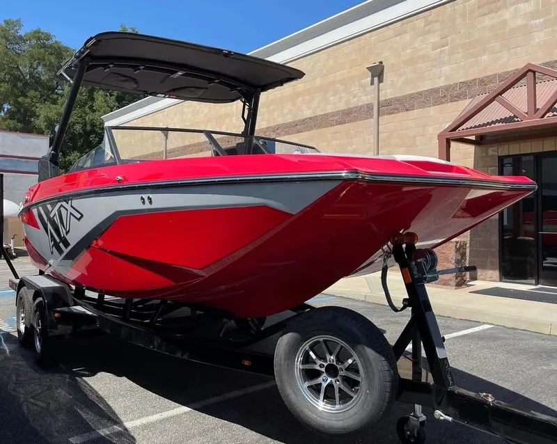 Slide: The Image of 2024 ATX 20 Type-S red and gray boat on a trailer outside a building. - 3