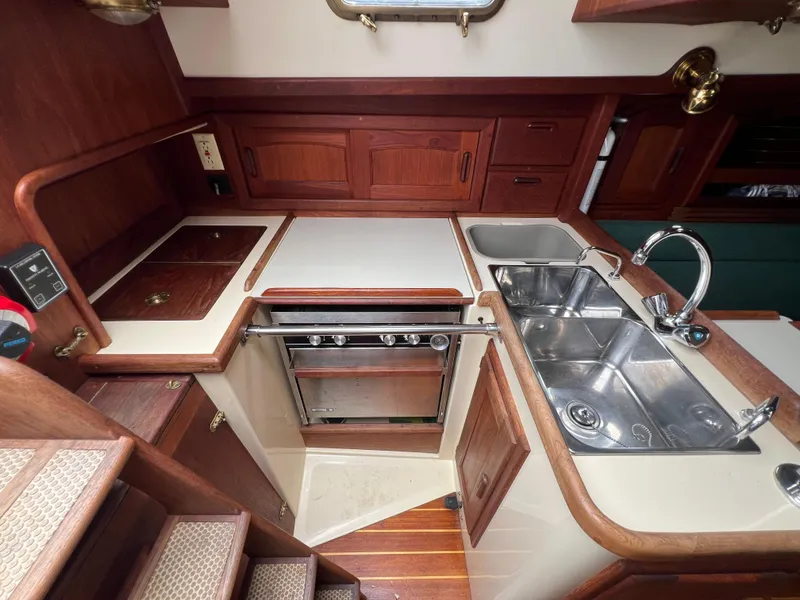 Slide: The Image of 1994 Pacific Seacraft 34 galley with stove, sink, and wooden cabinetry. - 35