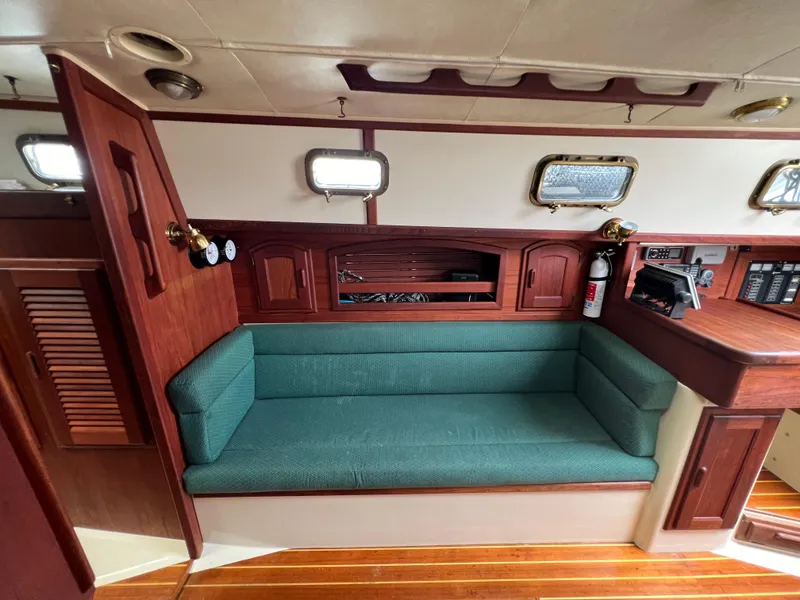 Slide: The Image of Interior of 1994 Pacific Seacraft 34 sailboat with green cushioned seating and wooden cabinetry. - 49