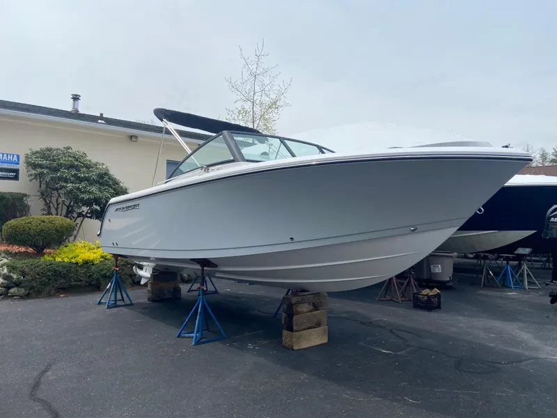 The Image of 2024 Aquasport 2200 Dual Console boat on stands in a parking lot. - 1