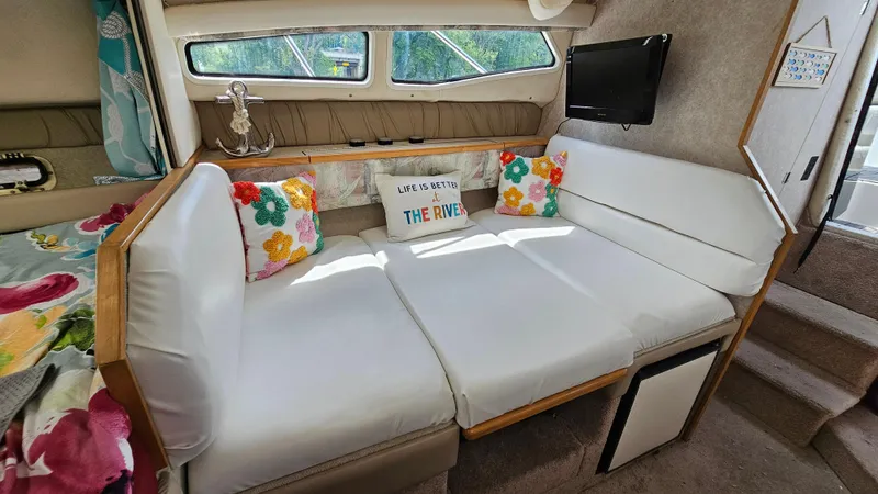 Slide: The Image of Interior of 1998 Bayliner 2855 Ciera with white seating and colorful pillows. - 16