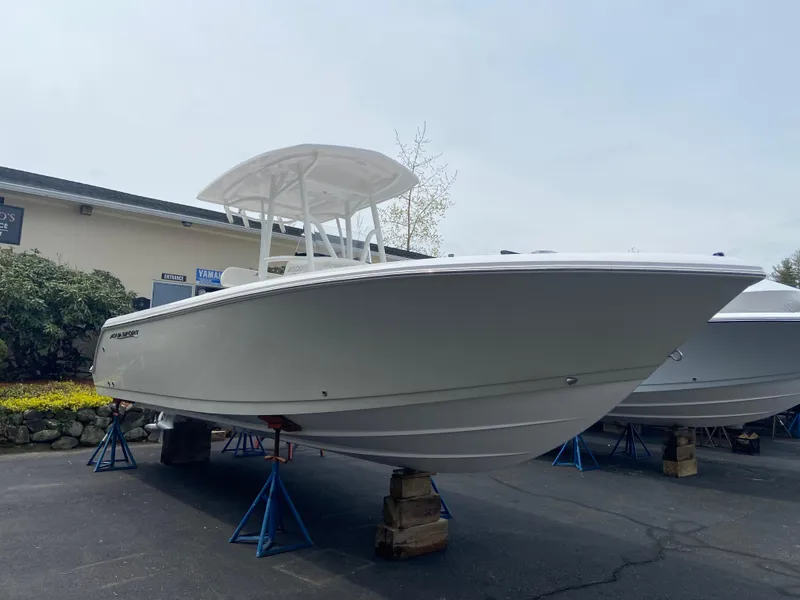 The Image of 2024 Aquasport 2400CS boat on stands in a parking lot. - 1