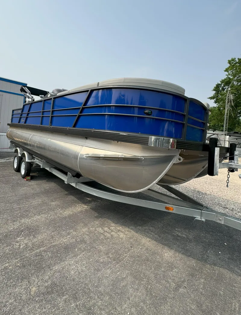 Slide: The Image of 2024 Massimo Marine P24-Limited Lounge Tritoon on trailer, blue exterior. - 3