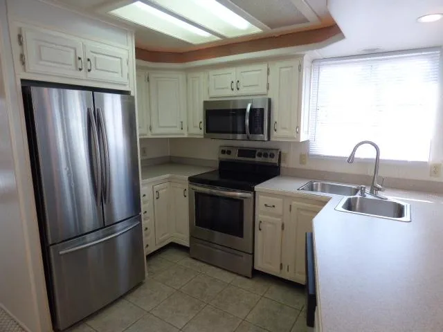 Slide: The Image of Modern kitchen with stainless steel appliances, white cabinets, and large window. Sunstar 16x65, 2003 model. - 4