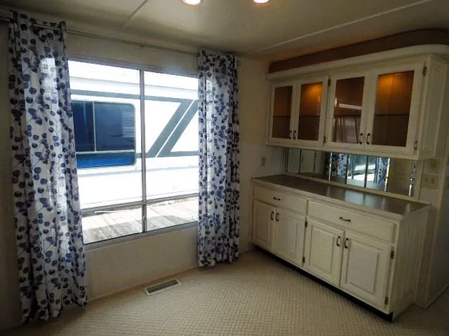 Slide: The Image of Dining area in a 2003 Sunstar 16x65 houseboat with wooden table and white cabinetry. - 5