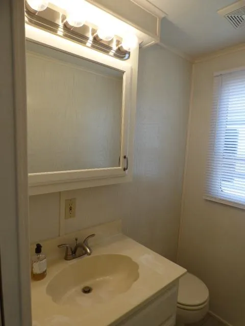 Slide: The Image of Compact bathroom with vanity, mirror, and window in a 2003 Sunstar 16x65 houseboat. - 7