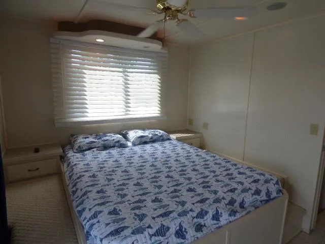 Slide: The Image of 2003 Sunstar 16x65 houseboat bedroom with bed, window blinds, and ceiling fan. - 8