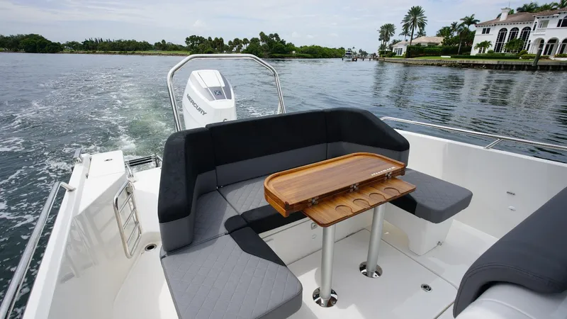Slide: The Image of 2024 Nimbus Tender 9 #143 boat with cushioned seating and wooden table on water. - 13