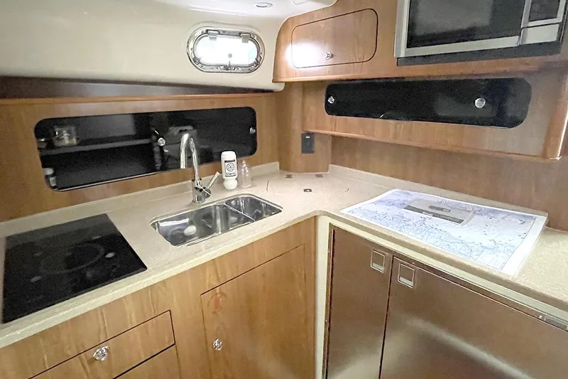 Slide: The Image of 2009 Pursuit OS 375 Offshore boat kitchen with sink, stove, and storage cabinets. - 16