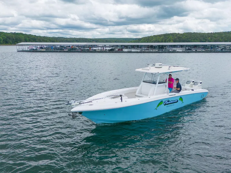 Slide: The Image of 2019 Fountain 34CC boat cruising on a lake with a marina in the background. - 1