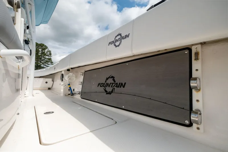 Slide: The Image of 2019 Fountain 34CC boat interior with logo, white deck, and storage compartments. - 14