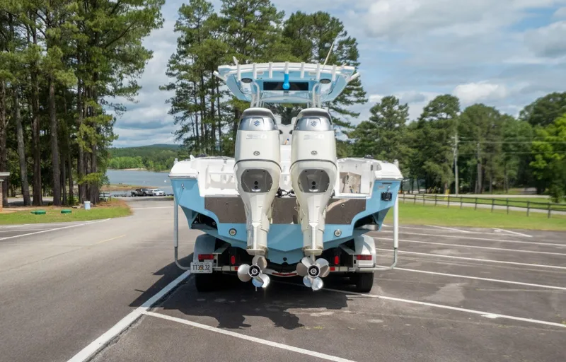 Slide: The Image of 2019 Fountain 34CC boat with twin outboard engines on a trailer in a parking lot. - 17