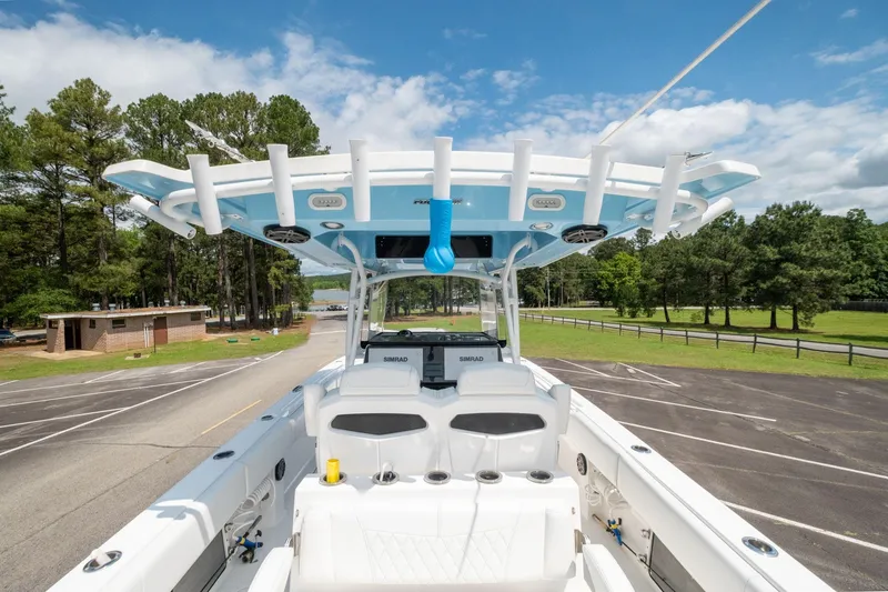 Slide: The Image of 2019 Fountain 34CC boat with T-top and rod holders in a parking lot. - 7