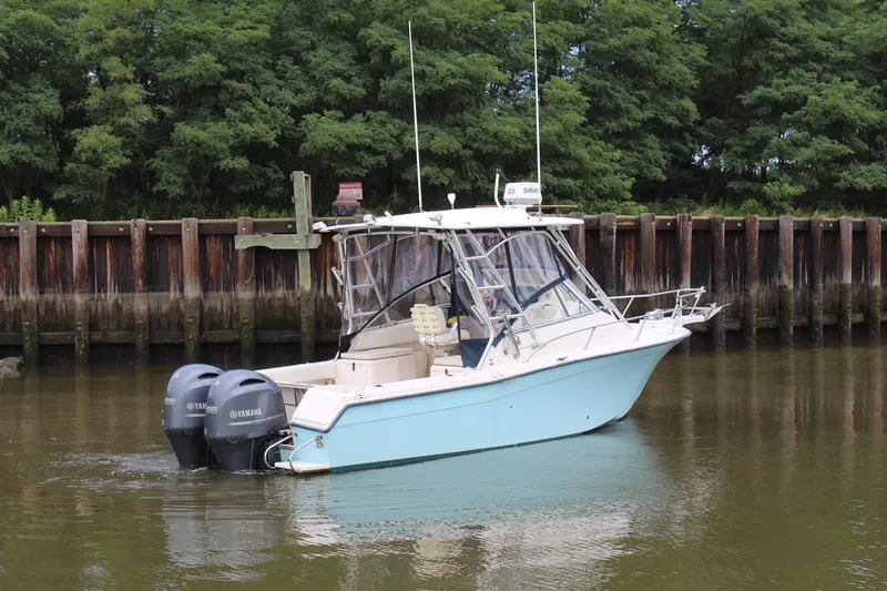 Slide: The Image of 2002 Grady-White Express 265 boat with twin Yamaha engines docked in calm water. - 32