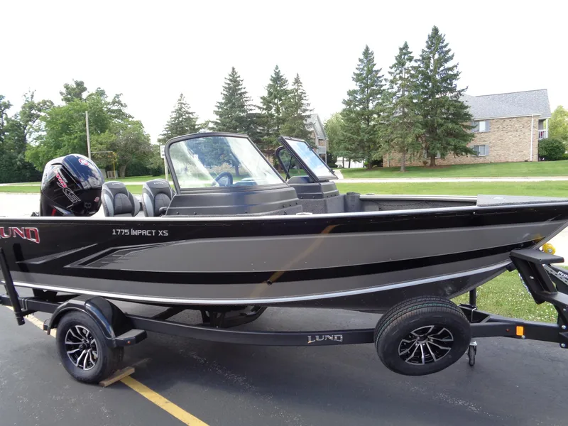 The Image of 2024 Lund 1775 Impact XS fishing boat on trailer, parked outdoors. - 0