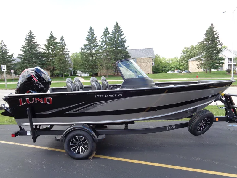 Slide: The Image of 2024 Lund 1775 Impact XS fishing boat on trailer, parked outdoors. - 1