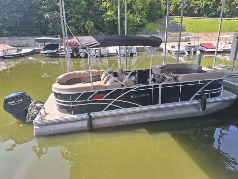 Slide: The Image of 2025 Sylvan Mirage 822 LZ pontoon boat docked on a calm lake. - 2