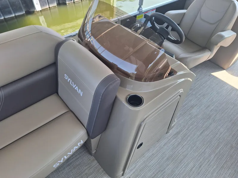 Slide: The Image of 2025 Sylvan Mirage 822 LZ boat interior with beige seating and steering console. - 6