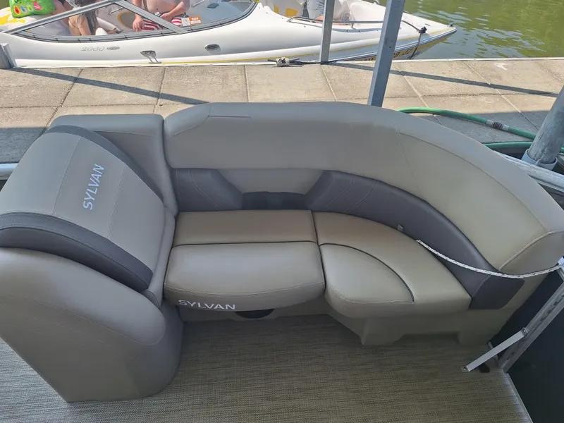 Slide: The Image of 2025 Sylvan Mirage 822 LZ boat seating, gray upholstery, docked by water. - 7