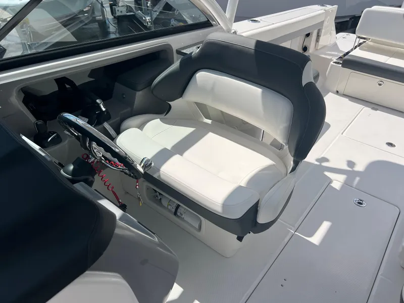 Slide: The Image of 2024 Robalo R317 Dual Console boat interior with white captain's seat and steering wheel. - 21