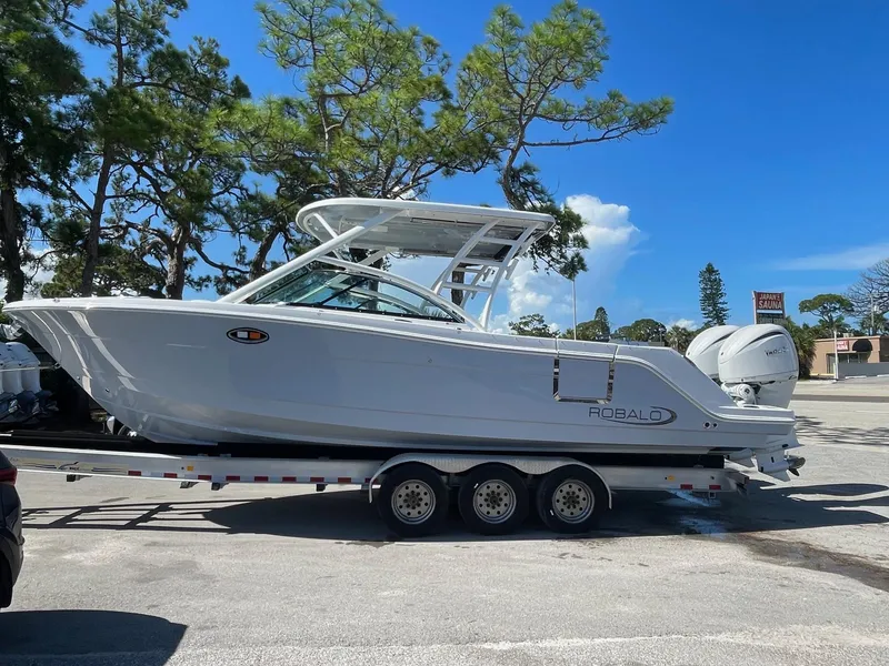 Slide: The Image of 2024 Robalo R317 Dual Console boat on a trailer in a parking lot. - 3