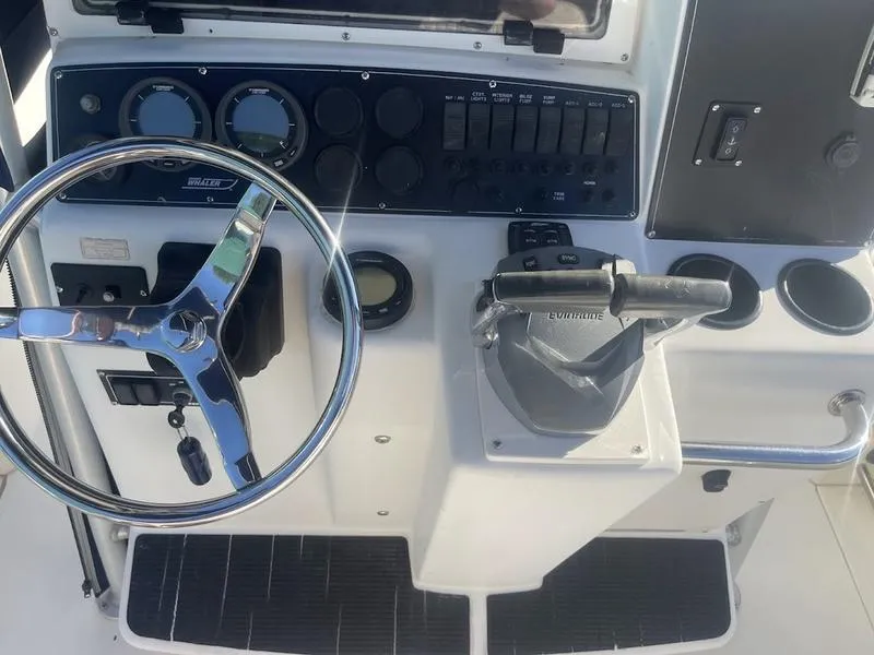 Slide: The Image of Control panel of a 2000 Boston Whaler 260 Outrage boat, featuring steering wheel and throttle. - 4