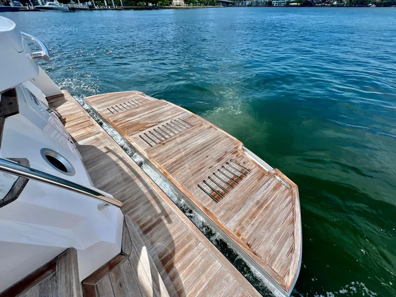 Slide: The Image of 2022 OKEAN Flybridge 50 yacht with extended wooden swim platform on calm water. - 46