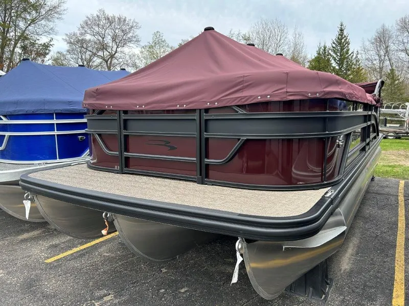 Slide: The Image of 2024 Bennington 22SSR pontoon boat with maroon cover in parking lot. - 1