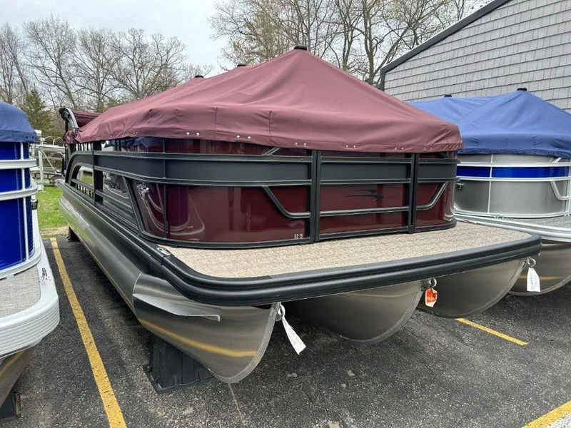 Slide: The Image of 2024 Bennington 22SSR pontoon boat with maroon cover in parking lot. - 2