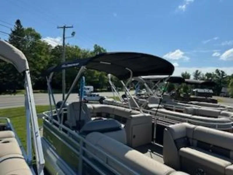 Slide: The Image of 2024 Sun Tracker SF 20 DLX pontoon boat with canopy, parked outdoors. - 8