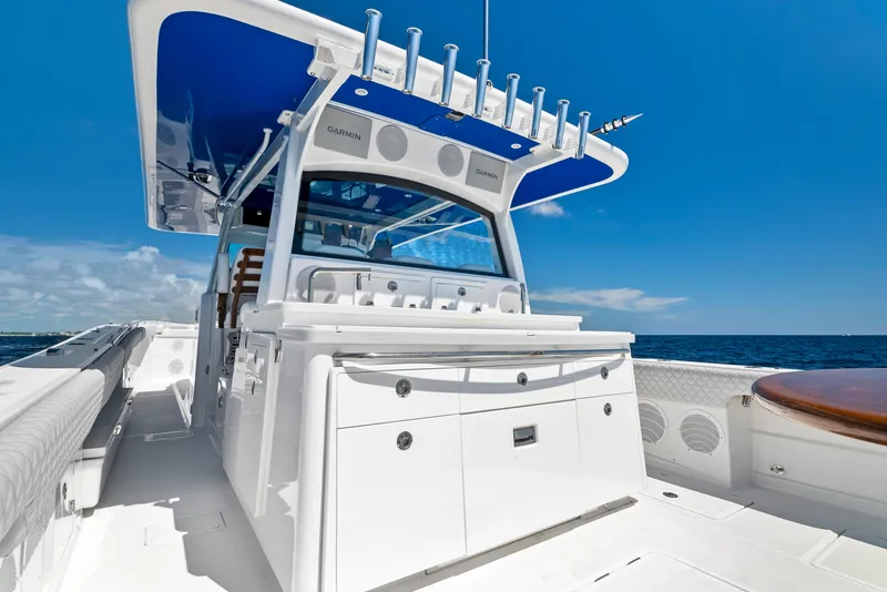 Slide: The Image of 2022 HCB Suenos boat with sleek design, white deck, and blue canopy on open sea. - 13
