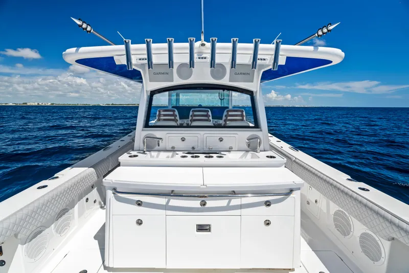 Slide: The Image of 2022 HCB Suenos boat interior with fishing rod holders, ocean view, and clear blue sky. - 14