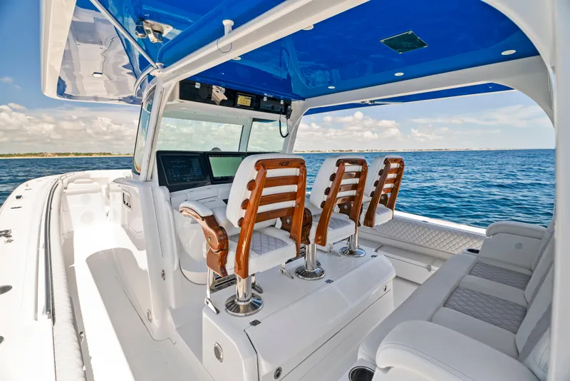 Slide: The Image of 2022 HCB Suenos boat interior with wooden seats and blue canopy on open water. - 27