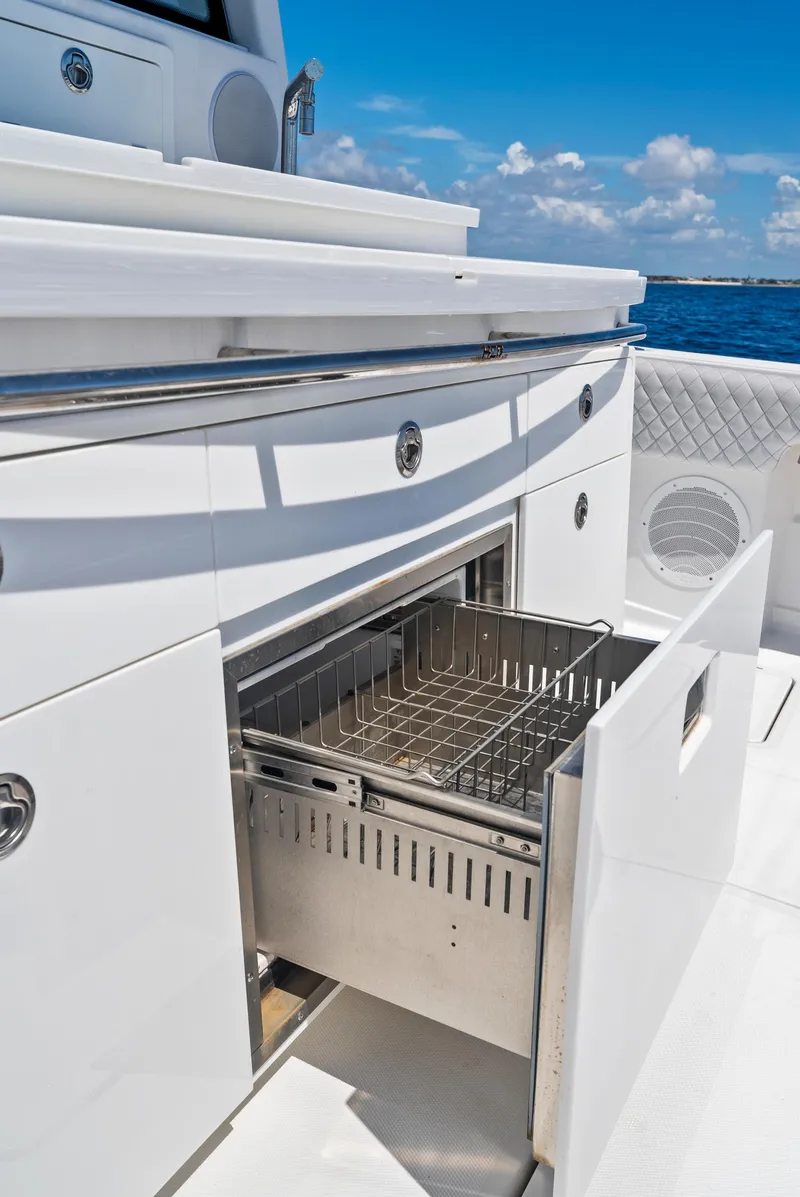 Slide: The Image of 2022 HCB Suenos boat with open storage compartment, sleek white design, and ocean backdrop. - 30