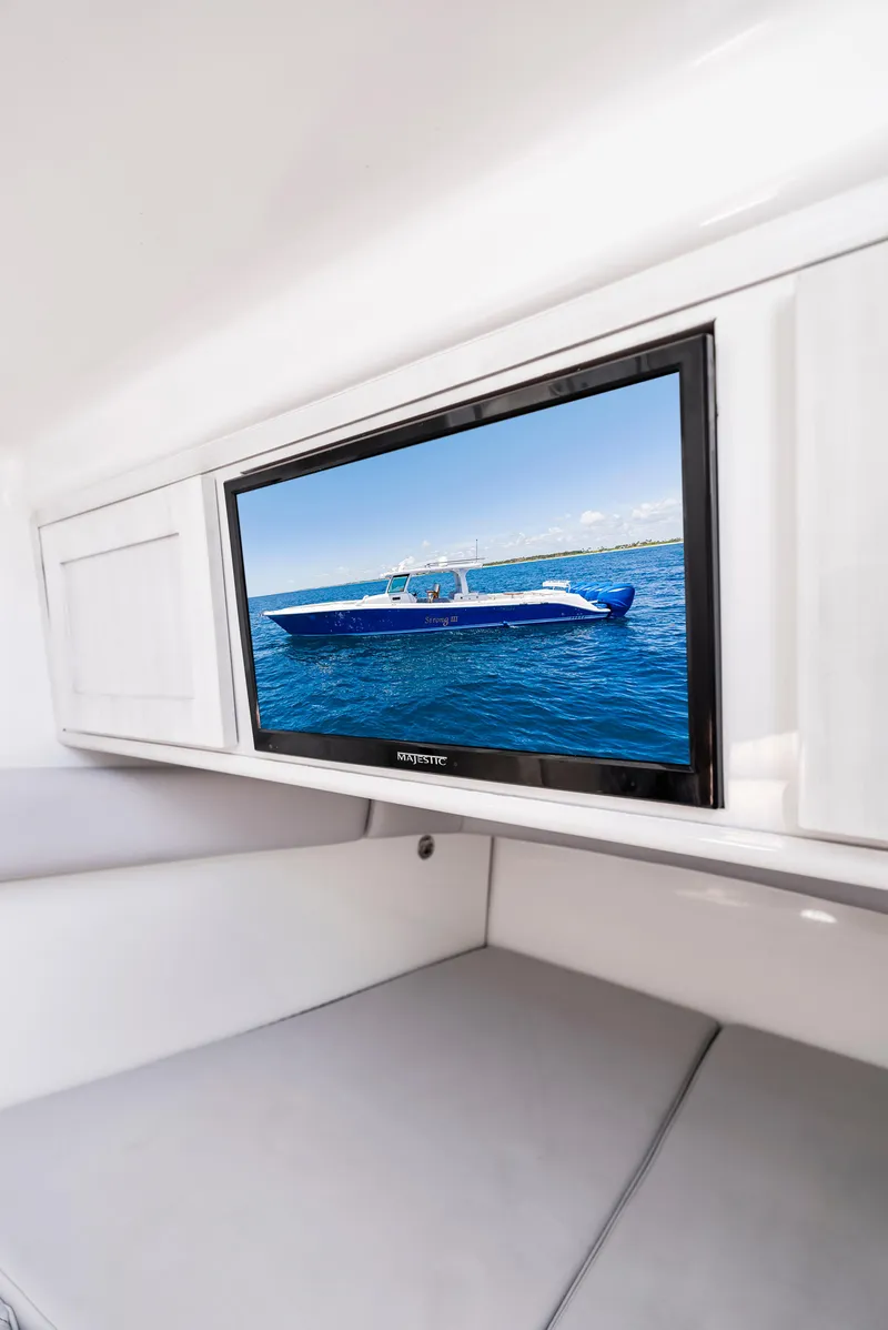Slide: The Image of 2022 HCB Suenos boat interior with wall-mounted TV displaying a blue boat on the water. - 40