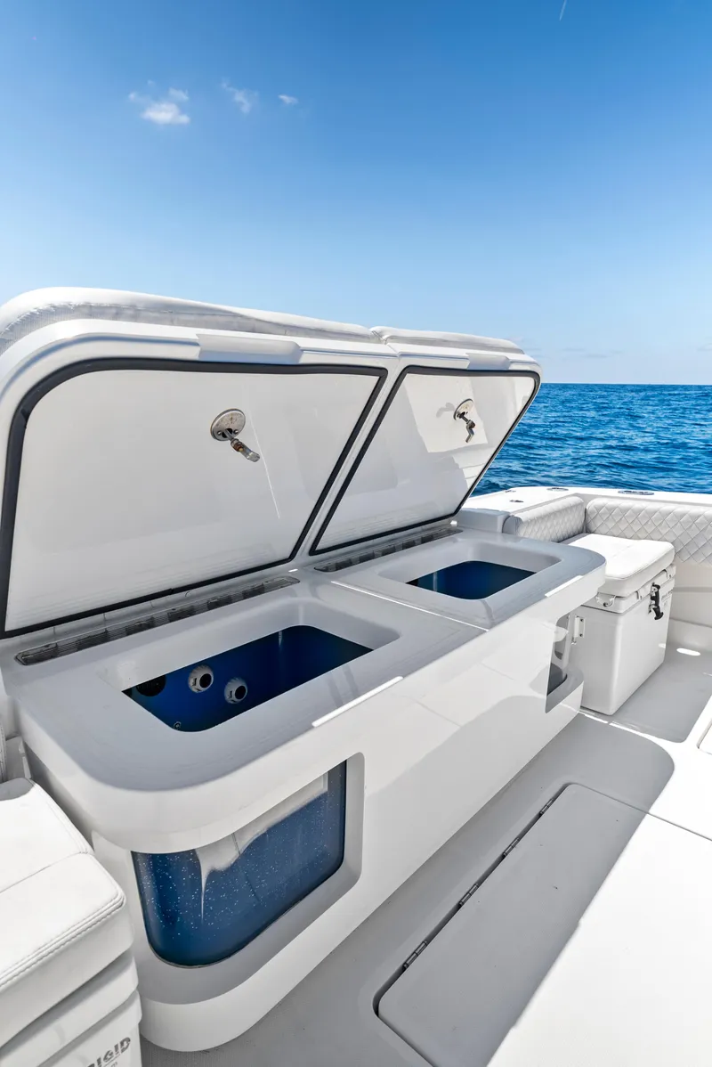 Slide: The Image of 2022 HCB Suenos boat with open storage compartments, ocean view, and clear blue sky. - 37