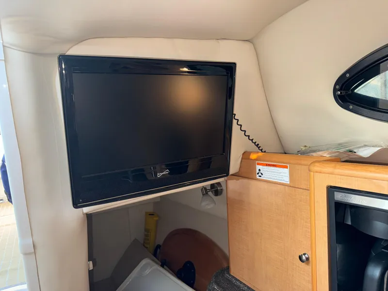 Slide: The Image of 2011 Glastron GS 289 cabin interior with mounted TV and wooden cabinetry. - 47