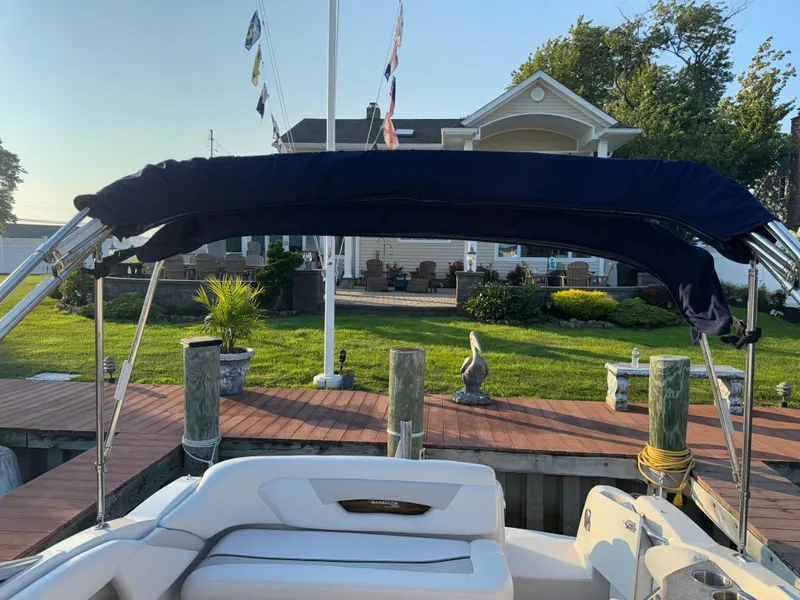 Slide: The Image of 2011 Glastron GS 289 boat docked, featuring a navy canopy and scenic waterfront view. - 17