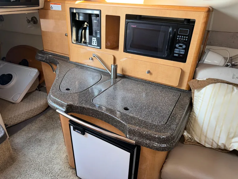 Slide: The Image of 2011 Glastron GS 289 boat kitchenette with sink, microwave, and mini fridge. - 38