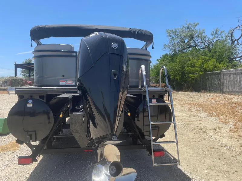 Slide: The Image of 2024 Regency 230 DL3 pontoon boat rear view with motor and ladder. - 2