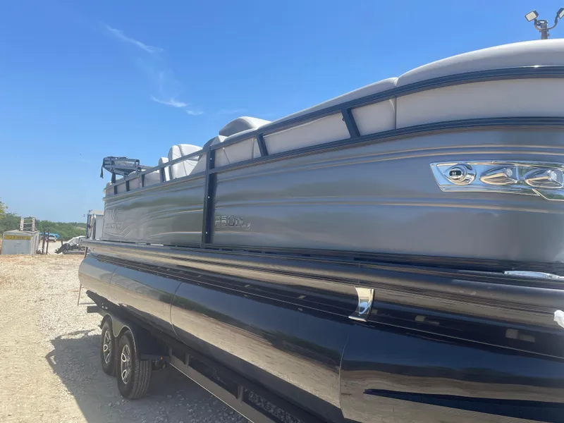 Slide: The Image of 2024 Regency 230 DL3 pontoon boat on a trailer under clear blue sky. - 4