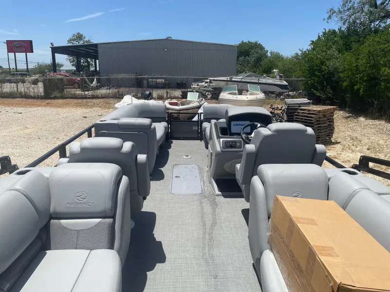 Slide: The Image of 2024 Regency 230 DL3 pontoon boat with spacious seating and modern dashboard, parked outdoors. - 5