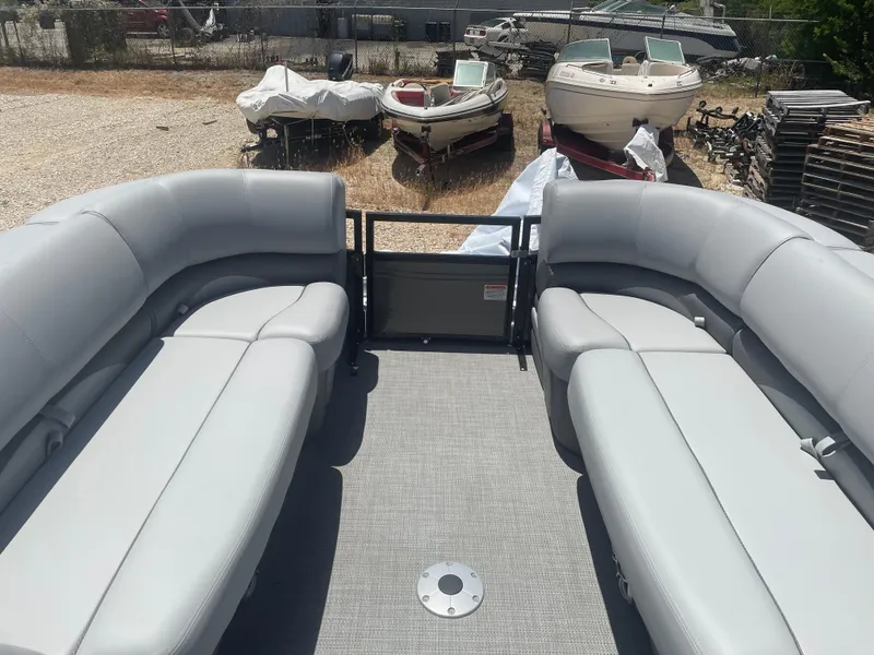 Slide: The Image of 2024 Regency 230 DL3 pontoon boat interior with gray seating, parked outdoors. - 6
