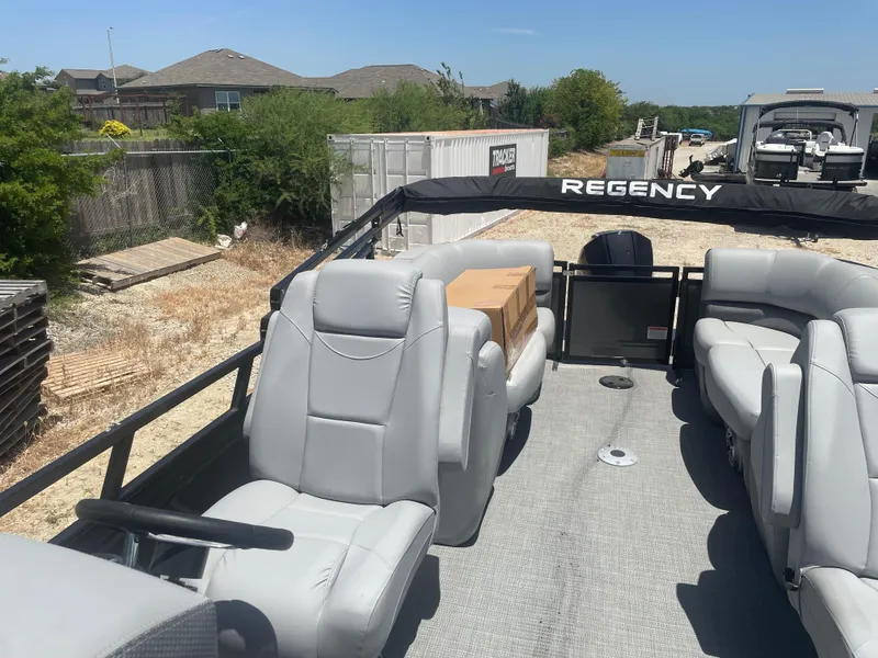 Slide: The Image of 2024 Regency 230 DL3 pontoon boat with gray seating, parked outdoors. - 9