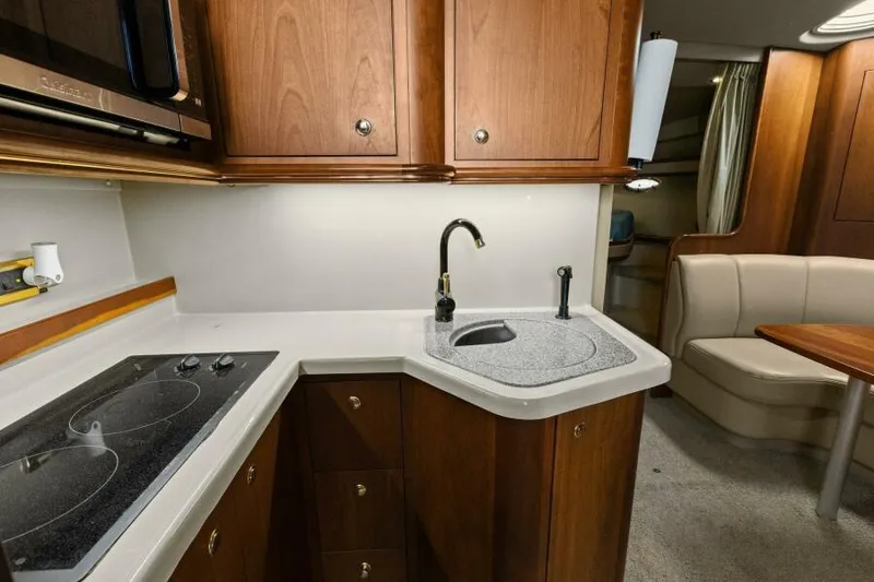 Slide: The Image of 2002 Cruisers Yachts 3672 Express kitchen with stove, sink, and wooden cabinetry. - 31