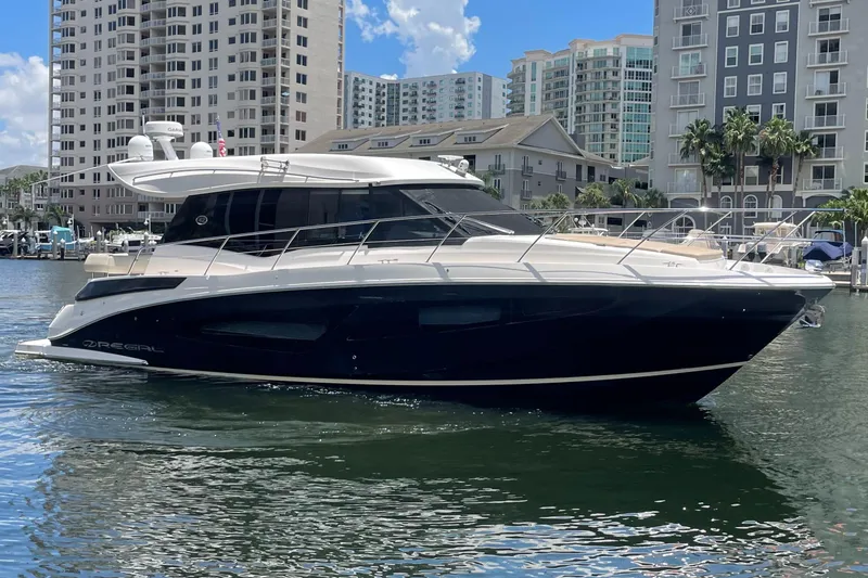 The Image of 2019 Regal 42 Grande Coupe yacht docked in a marina with cityscape background. - 0