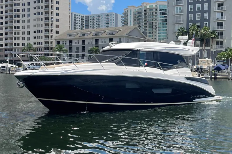 Slide: The Image of 2019 Regal 42 Grande Coupe yacht docked in a marina with high-rise buildings in the background. - 32