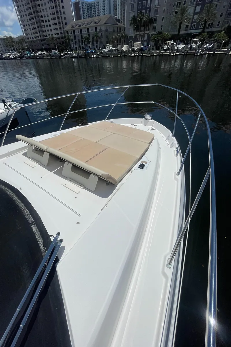Slide: The Image of 2019 Regal 42 Grande Coupe yacht with sunbathing area docked in a marina. - 7